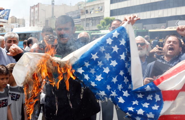 Demonstranci w Teheranie palą flagę USA na marszu poparcia dla decyzji rządu Iranu o wznownieniu programu atomowego / autor: PAP/EPA/ABEDIN TAHERKENAREH