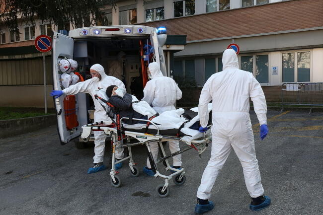 Ambulans i pielęgniarze ubrani w stroje ochronne transportują chorego do szpitala w Padwie (Italia) / autor: PAP/EPA/NICOLA FOSSELLA