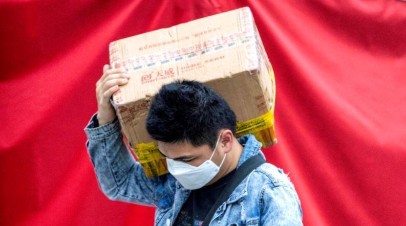Mężczyzna nosi na rynku paczkę z towarami na telefony komórkowe i sprzęt elektroniczny w Guangzhou, w prowincji Guangdong, w Chinach, 17 marca 2020 r / autor: PAP/EPA/ALEX PLAVEVSKI
