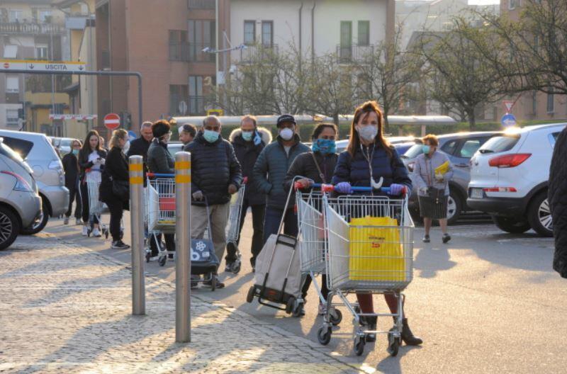 Kupujący w maskach na twarz czekają w długich kolejkach poza supermarketem w Desio, w północnych Włoszech, 21 marca 2020 r. / autor: PAP/EPA/SERGIO PONTORIERI