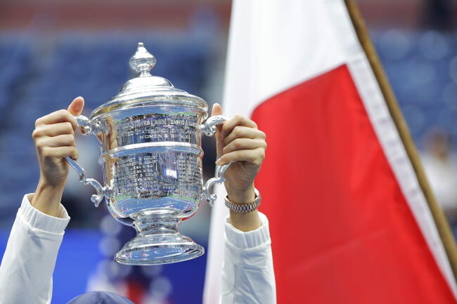 Uniesiony w rękach Igi puchar dla zwyciężczyni tenisowego turnieju US Open / autor: PAP/EPA/JUSTIN LANE