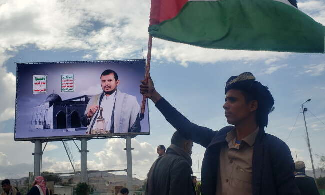 Bojownik Huti z flagą Jemenu. W tle wizerunek przywódcy Huti Abdul-Malika al-Houthi / autor: PAP/EPA/YAHYA ARHAB