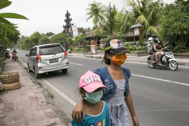 Ludzie na Bali noszą maski chroniące przed wulkanicznym pyłem / autor: fot. PAP/ EPA/MADE NAGI